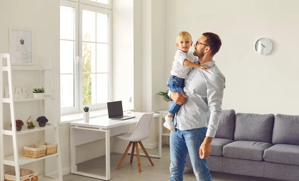 Jonge vader houdt zijn gelukkige zoontje staande in de gezellige kamer van hun nieuwe appartement — Stockfoto