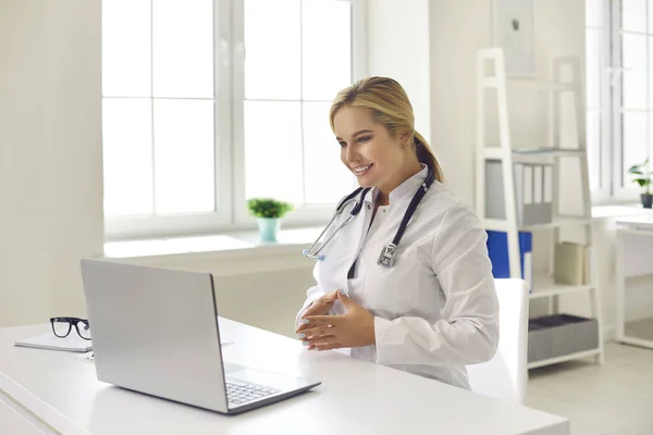 Lächelnder Arzt berät Patientin während Videotelefonie auf modernem Laptop — Stockfoto