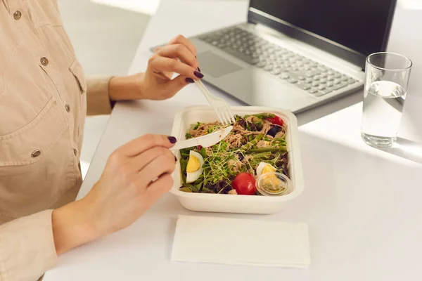 Hands of woman office worker eating healthy meal delivered by food delivery service