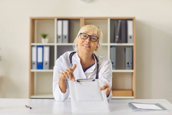 Médico amigável apontando para prescrição médica e explicando como tomar remédio — Fotografia de Stock