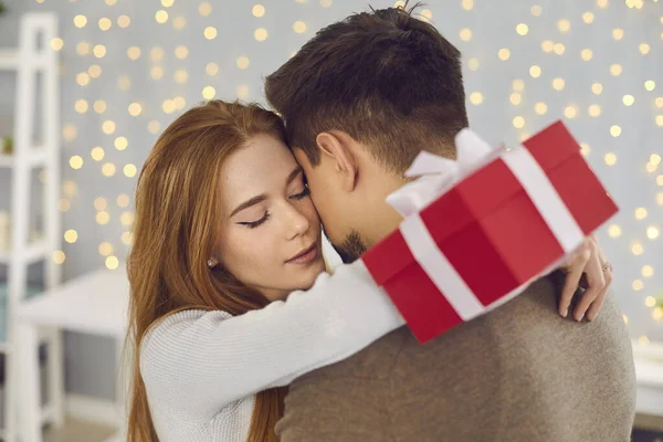 Happy woman and man couple hugging during giving presents and celebrating holiday at home — Stock fotografie
