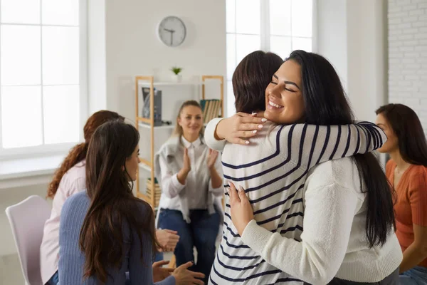 Happy young women hugging each other in support group meeting or therapy session — Stock Photo, Image