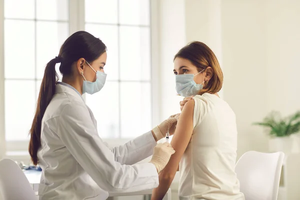 Infirmière professionnelle vaccinant une jeune femme pendant la campagne de vaccination au centre de santé — Photo