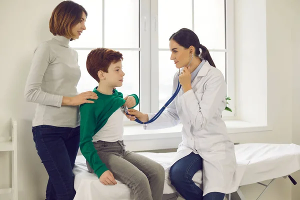 El médico coloca un estetoscopio en el pecho de un niño y escucha los latidos cardíacos y los pulmones de los niños pequeños.. —  Fotos de Stock