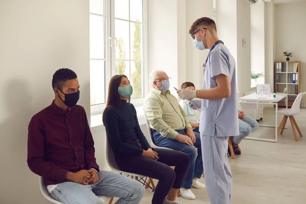 Young man doctor talking to waiting patients before vaccination agains virus — Stock Photo, Image