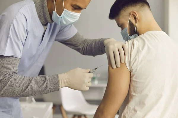 Médico en mascarilla facial inyectando a paciente con vacuna antiviral durante campaña de inmunización — Foto de Stock