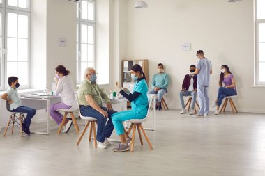 Maskeli doktorlar, salgın sırasında her yaştan insanları covid-19 virüsüne karşı aşılıyor..