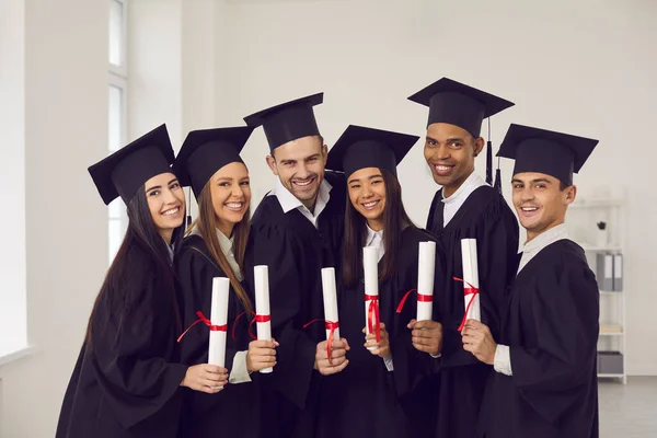 Porträtt av en grupp glada multiraciala akademiker med diplom i sina händer. — Stockfoto