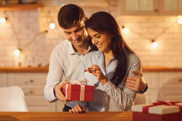 Mladá šťastná brunetka žena vybalování dovolená dárek od jejího usmívajícího se přítele — Stock fotografie