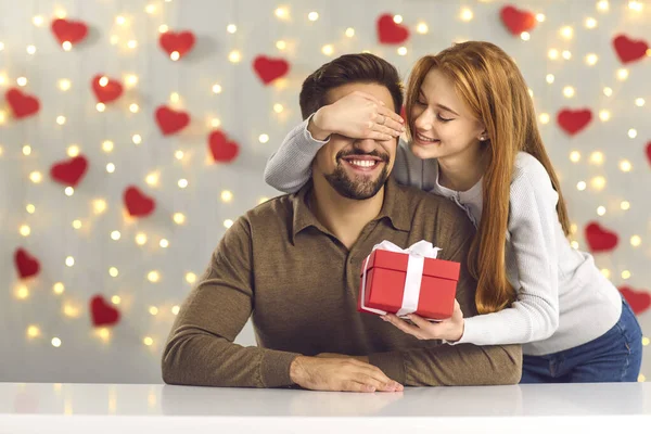 Feliz joven recibiendo regalo de su novia cariñosa en el día de San Valentín — Foto de Stock