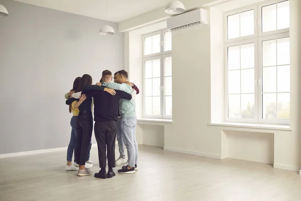 Ungdomar som står i cirkel på kontoret, kramar varandra och pratar. — Stockfoto