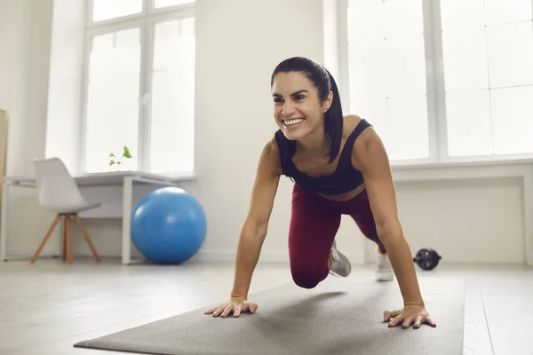 Güzel aktif spor kadını paspasın üzerinde antrenman yapıyor ve karantina sırasında evde bacak egzersizi yapıyor.. — Stok fotoğraf