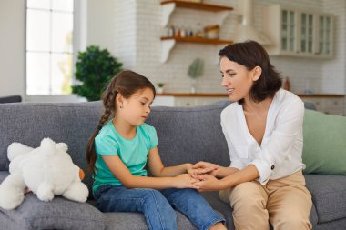 Üzgün kız, çocuk psikoloğuyla terapi seansı yapıyor. Kendi evinin mahremiyetinde kanepede oturuyor.