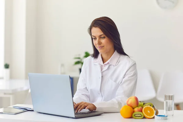 Giovane donna sorridente medico comunicare online con il paziente circa la dieta e il cibo sano — Foto Stock