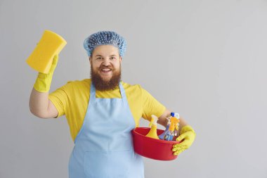 Önlüklü, sakallı, komik, şişman bir adam gri arka planda yıkanıyor..