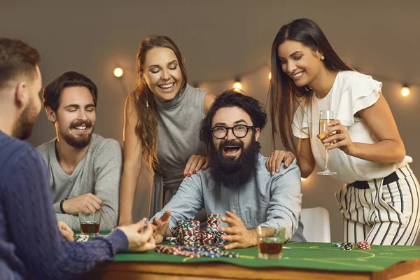 Gruppe lächelnder junger Leute mit Getränken gratuliert glücklichen Freund Gewinner im Poker — Stockfoto