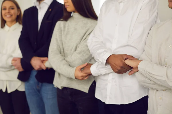 Equipe de pessoas de pé juntos e de mãos dadas, mostrando unidade e apoiando uns aos outros — Fotografia de Stock