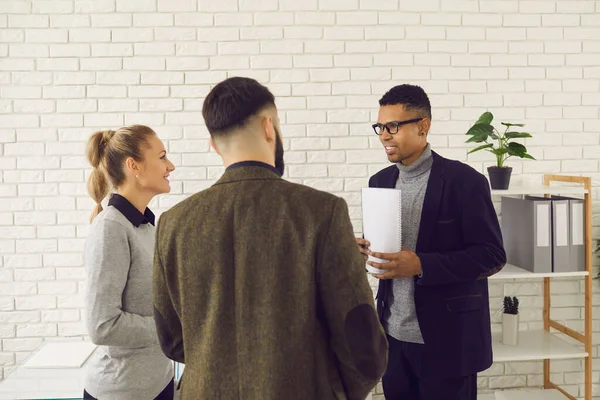 Equipo internacional socios comerciales multiétnicos colegas de pie en la oficina y discutir las tareas corporativas — Foto de Stock