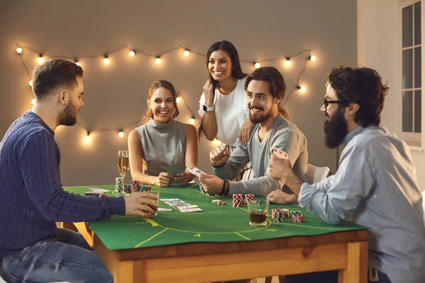 Alegre compañía de amigos hombres y mujeres sentados en una mesa de póquer y disfrutando de la noche. —  Fotos de Stock