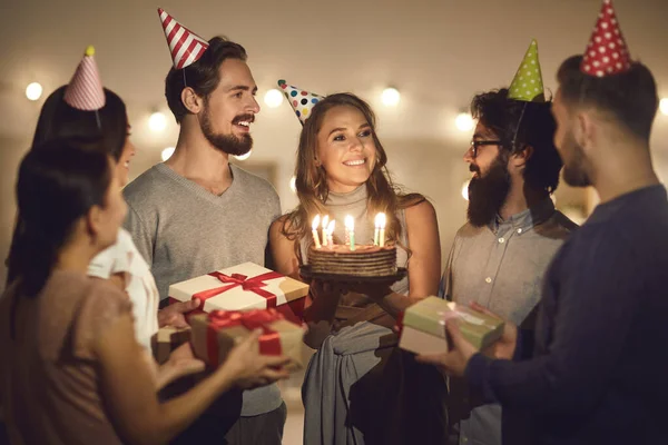 快乐的年轻女子拿着生日蛋糕，感谢朋友们的聚会和礼物 — 图库照片