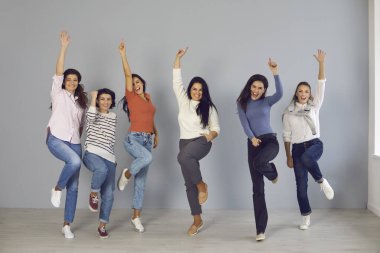 Bir grup mutlu genç kadın sevinçten zıplıyor ve gülüyor, takım başarısını kutluyor.
