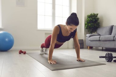 Keyifli genç bir kadın spor paspasında spor yaparken evde spor yapıyor.