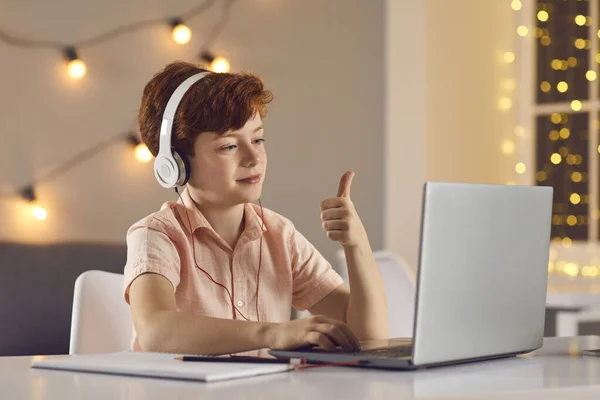 Pequeño niño muestra gesto fresco mirando a la pantalla del ordenador portátil mientras chatea a través de videollamada. — Foto de Stock