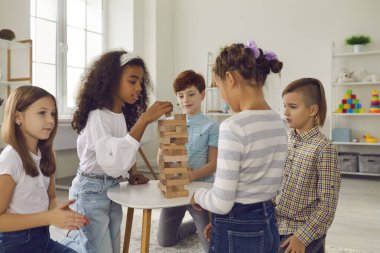 Bir grup karışık ırk çocuk arkadaşları evlerinde birlikte ahşap piramit inşa ediyorlar.
