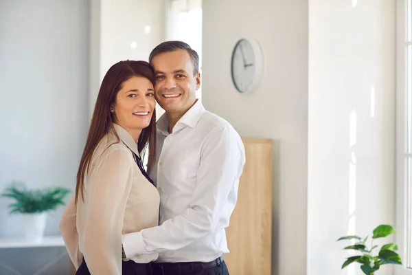 Mutlu çift birbirine sarılıyor ve şirket ofisinde duran kameraya bakıyor. — Stok fotoğraf