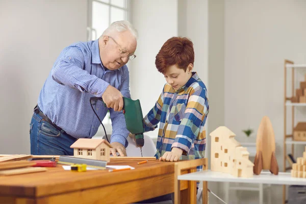 Nonno insegna al nipote a lavorare con il legno e spiega come usare il trapano — Foto Stock