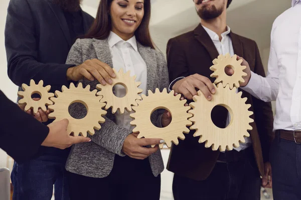 Sorrindo jovens empresários colegas ou equipe consertando engrenagens de madeira juntos — Fotografia de Stock