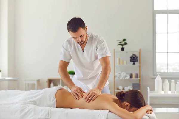 Ung kvinna ligger på en massage bord under en wellness kropp massage session i en massage salong. — Stockfoto