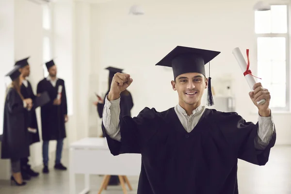 Abschluss mit Diplom in der Hand im Büro vor dem Hintergrund seiner Klassenkameraden. — Stockfoto