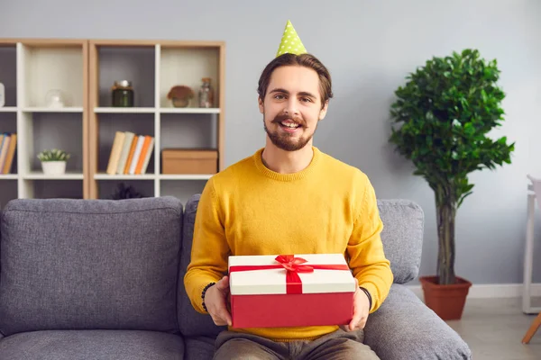 Cheerful man with a gift in his hands remotely congratulates a person on his birthday via webcam. — Stock Photo, Image