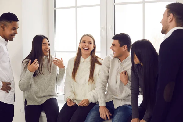 Groep gelukkige jonge collega 's, studenten of vrienden praten over grappige dingen en lachen — Stockfoto