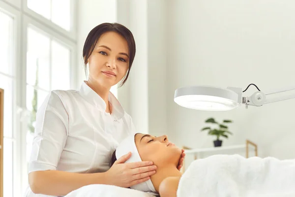 Vrouw dermatoloog aanraken van jonge vrouwen gezicht tijdens het controleren van de huid of massage — Stockfoto