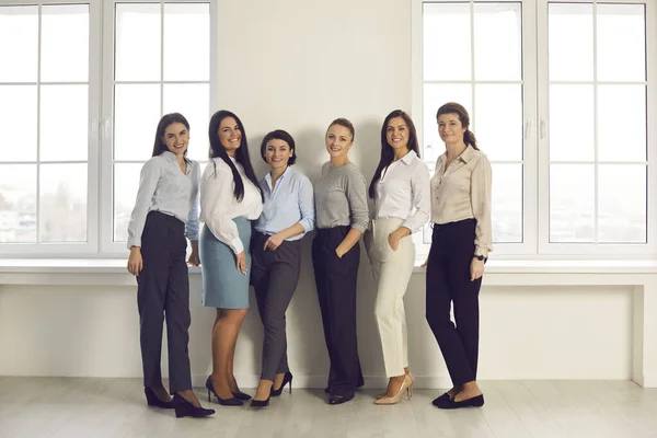 Team av glada affärskvinnor står tillsammans på nytt kontor och ler mot kameran — Stockfoto