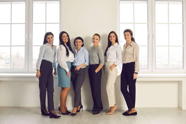 Команда счастливых деловых женщин, стоящих вместе в новом офисе и улыбающихся перед камерой