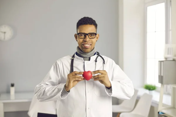 Arzt hält rotes Herz, blickt in die Kamera und bittet Sie, sich um Ihre Gesundheit zu kümmern — Stockfoto