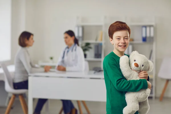 Portret szczęśliwego chłopca przytulającego misia w klinice w pokoju szpitalnym. — Zdjęcie stockowe