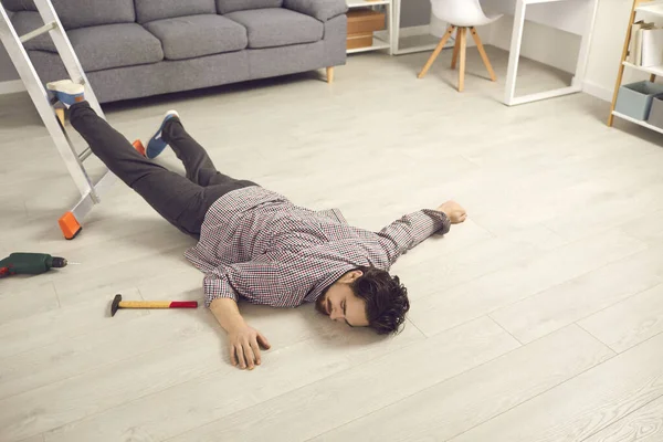Giovane che è caduto dalla scala mentre faceva riparazioni a casa sdraiato privo di sensi sul pavimento — Foto Stock