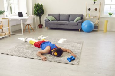 Yorgun genç bir adam başarısız olduktan ve spor yapmayı bıraktıktan sonra yerde yatıyor.