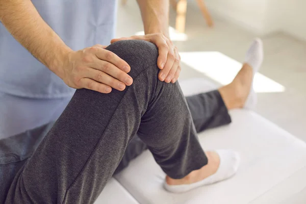 Manos del médico profesional osteópata revisando a los pacientes de rodilla durante la visita —  Fotos de Stock