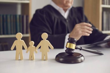 Gavel ses bloğunda ve küçük aile üyesi figürleri mahkeme masasında.