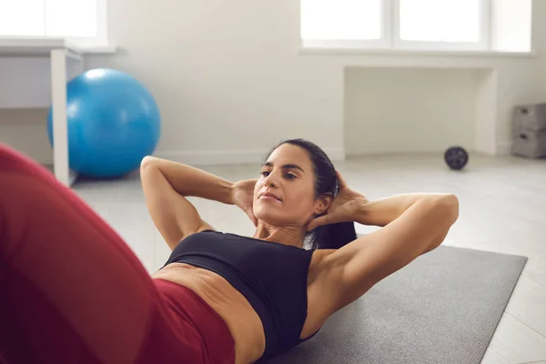 Mujer en forma haciendo abdominales o abdominales en la estera del gimnasio durante el entrenamiento deportivo de rutina en casa — Foto de Stock