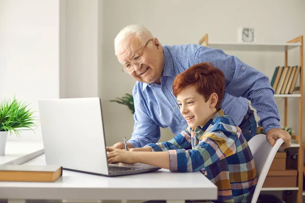 Heureux grand-père aide petit-fils avec les devoirs ou demande petit garçon pour lui apprendre à utiliser l'ordinateur — Photo