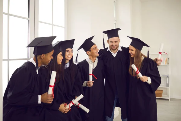 Grupp glada internationella universitetsstudenter med diplom firar examen — Stockfoto