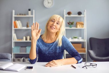 Yetişkin bayan öğretmen karantina sırasında öğrencilerini karşılamak için elini sallıyor..