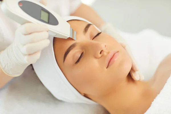 Womans rosto recebendo aparelho de ultra-som limpeza facial de cosmetologista profissional — Fotografia de Stock
