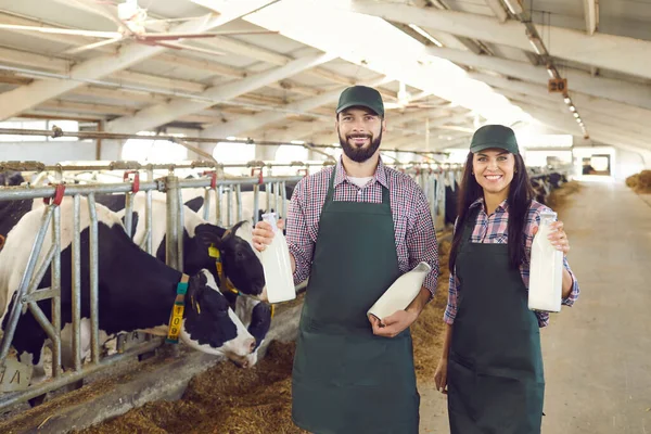 Enkele jonge boeren met glazen flessen verse, heerlijke biologische melk op de boerderij. — Stockfoto